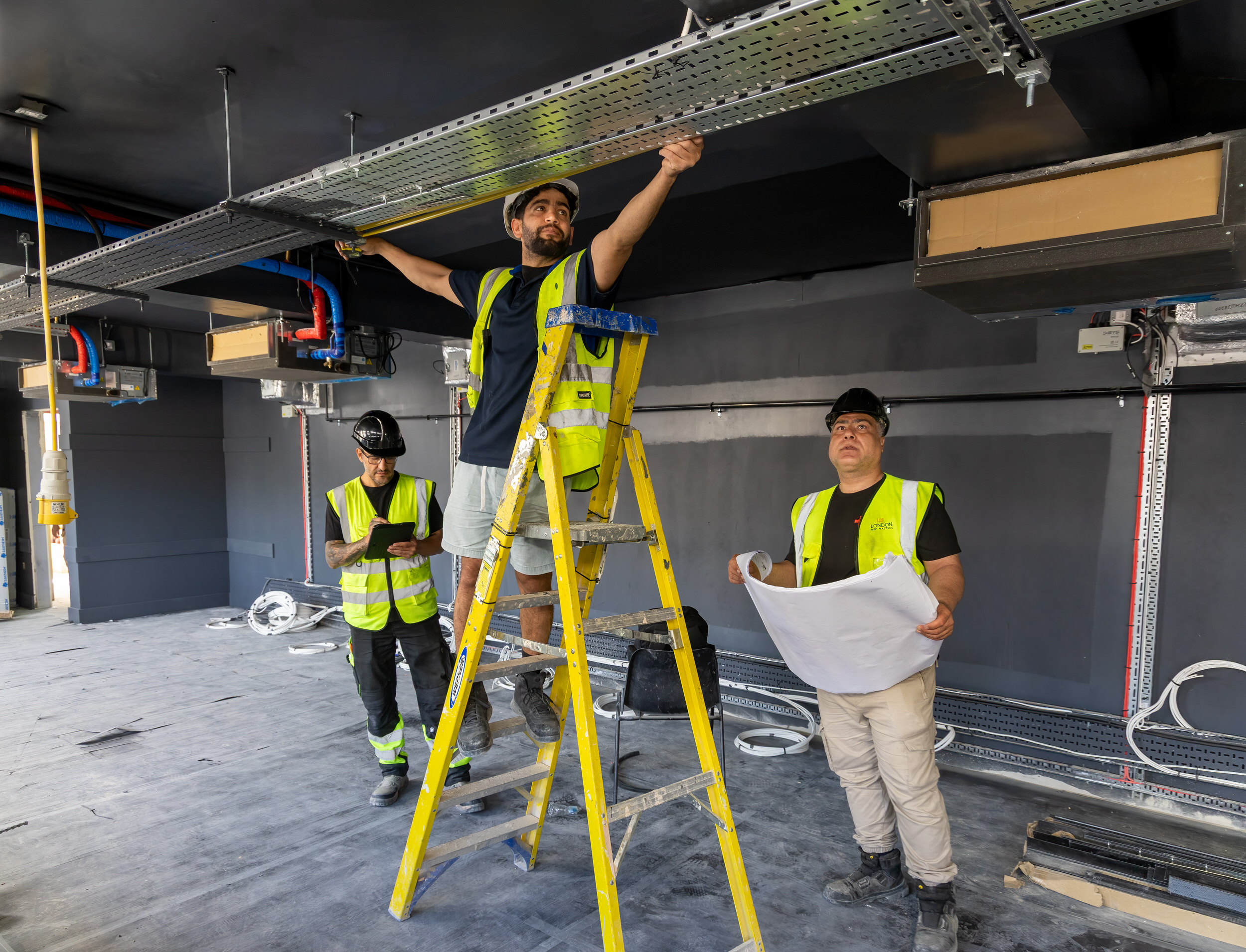 Engineers coordinating a design-and-build MEP installation from drawings on site