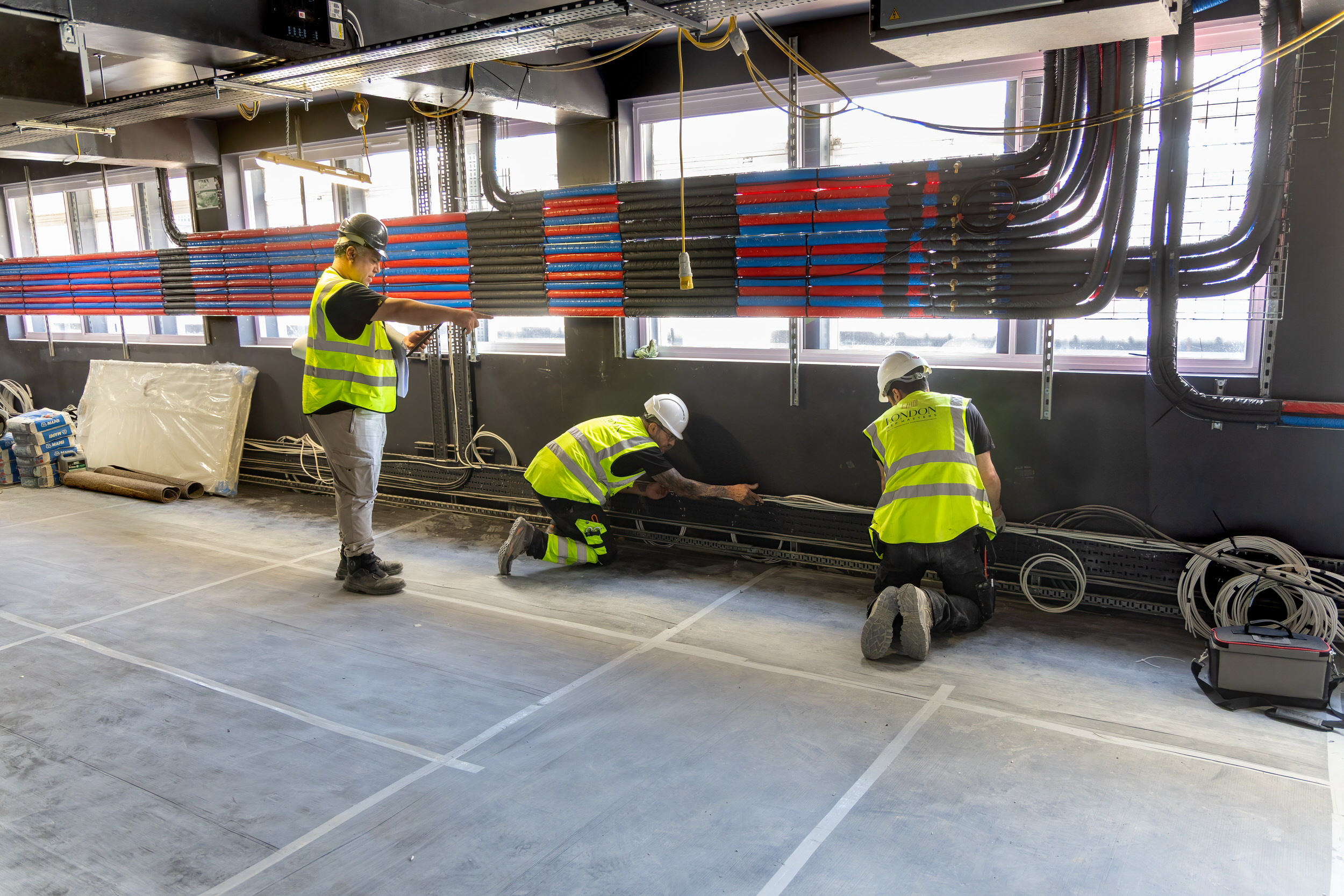 Electricians pulling power and data cables onto overhead containment