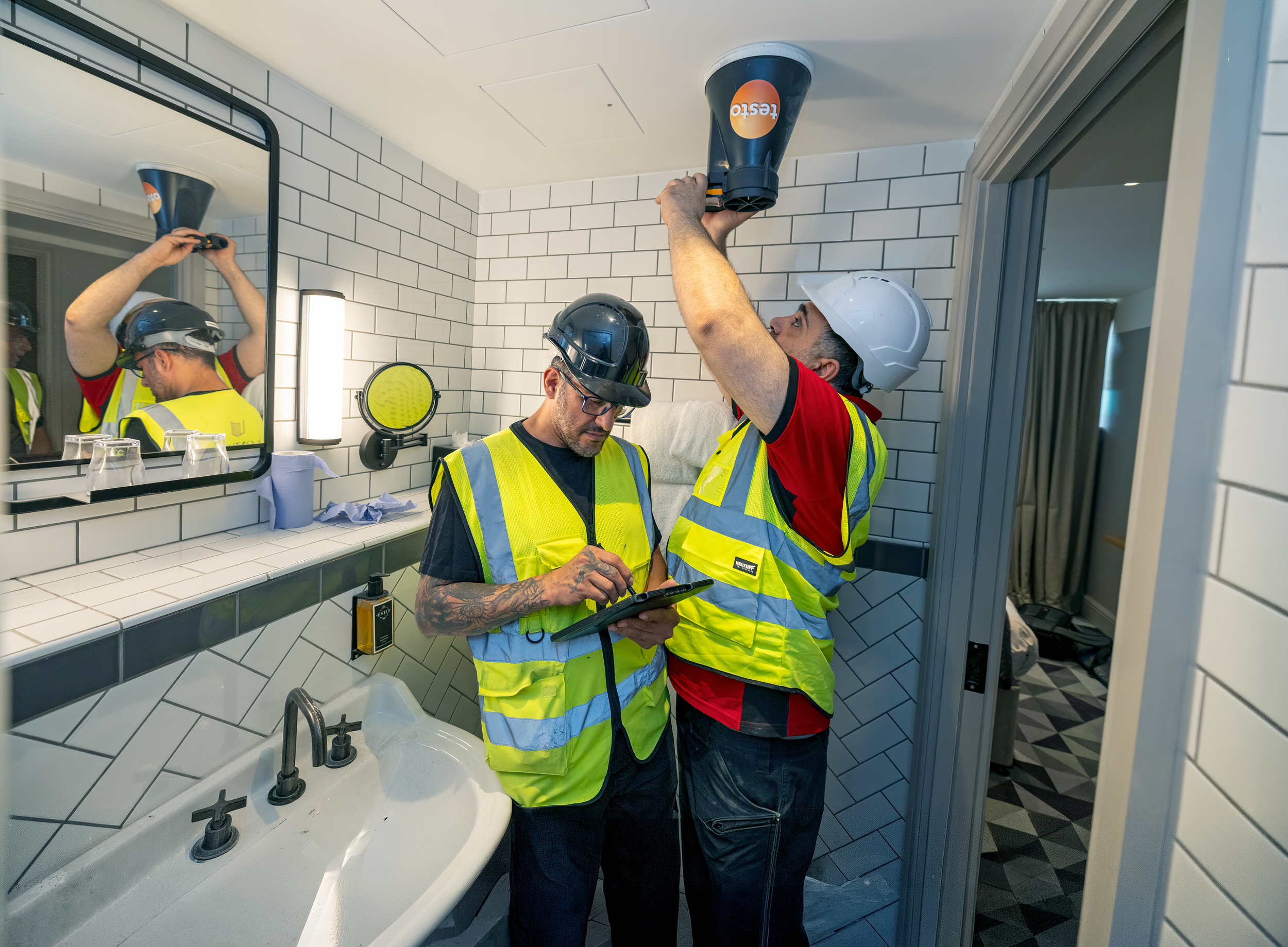 Engineers installing and setting a ceiling light fitting
